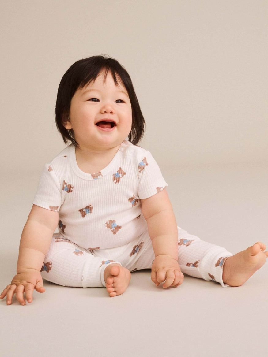 Baby Huxbaby Tumbling Bow Huxette Short Sleeve Bodysuit featuring a cute Huxette print design on a soft baby bodysuit with short sleeves and snap closures.