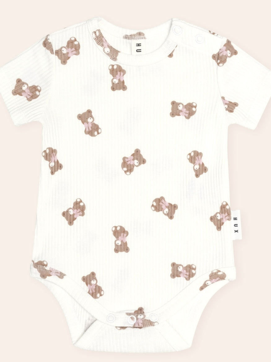 Front Huxbaby Tumbling Bow Huxette Short Sleeve Bodysuit featuring a cute Huxette print design on a soft baby bodysuit with short sleeves and snap closures.