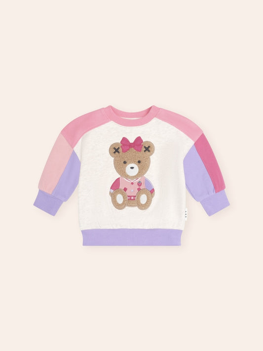 Colour block sweatshirt featuring a playful Sitting Huxette character graphic on the front. The cosy long-sleeve jumper combines contrasting colour panels with a relaxed fit and soft design, creating a fun and comfortable everyday style for kids.