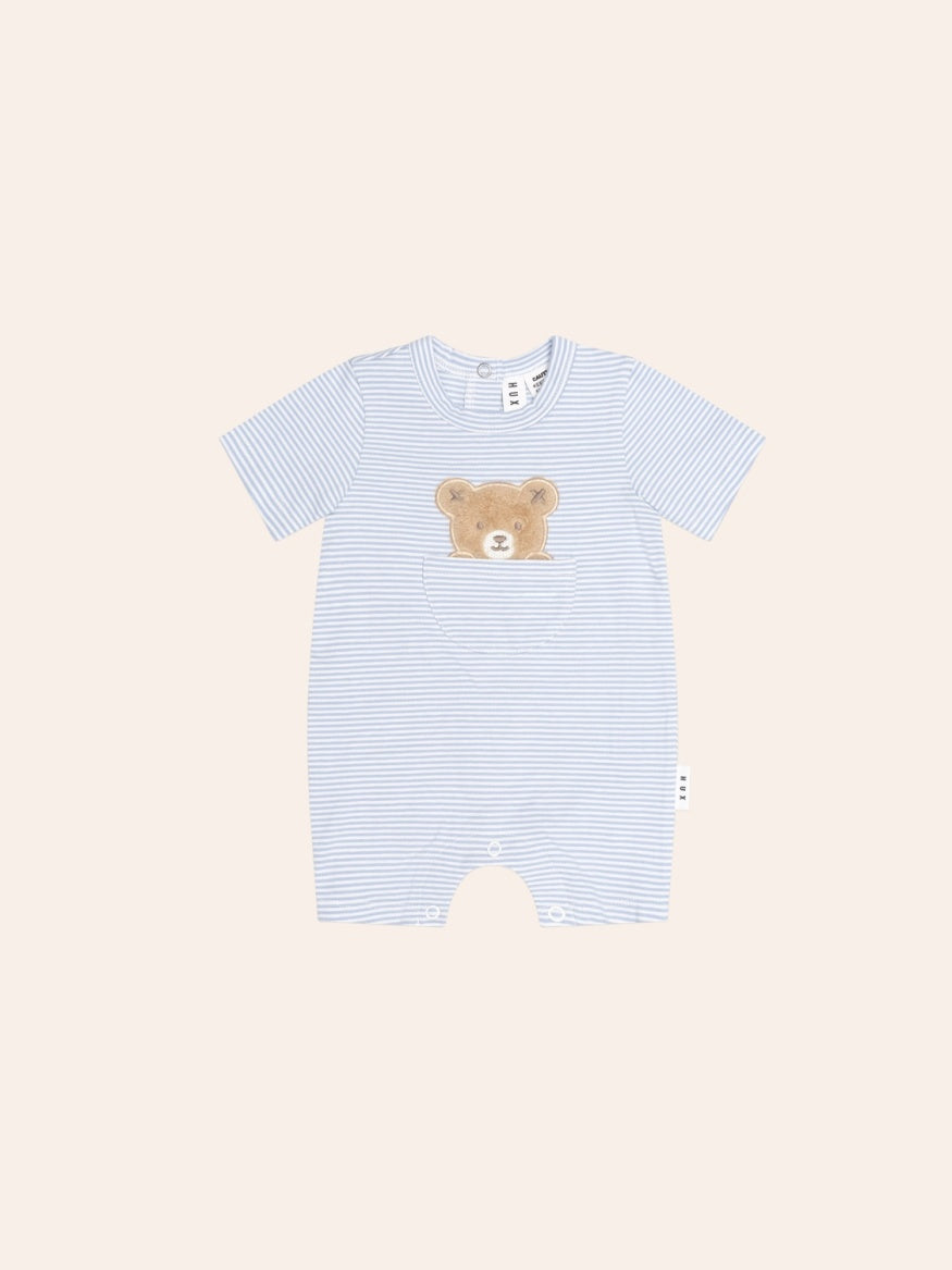 Baby bodysuit in a cream and beige striped pattern with a playful peekaboo bear face on the front. The long-sleeve, snap-crotch design features soft cotton fabric and a relaxed fit, with the bear graphic peeking from a front pocket for a cute, minimalist look.