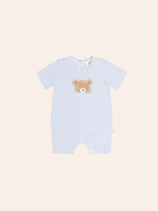 Baby bodysuit in a cream and beige striped pattern with a playful peekaboo bear face on the front. The long-sleeve, snap-crotch design features soft cotton fabric and a relaxed fit, with the bear graphic peeking from a front pocket for a cute, minimalist look.