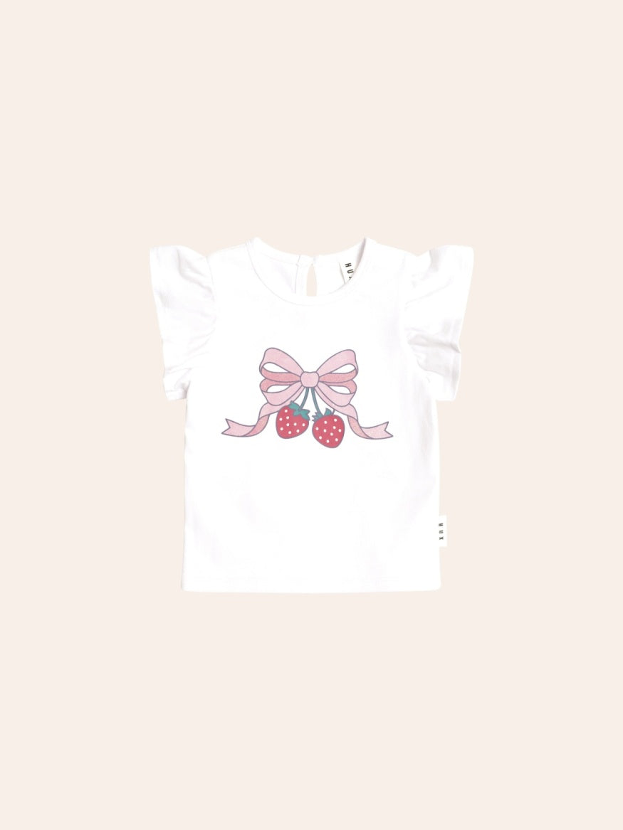 Soft pink short-sleeve T-shirt with delicate frill sleeves and a crew neckline. The front features a sweet strawberry graphic accented with a bow, creating a playful, whimsical look. The relaxed fit makes it ideal for everyday wear.