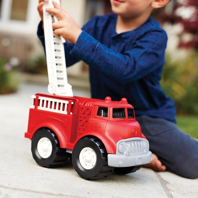 Child playing with a red toy fire truck outdoors