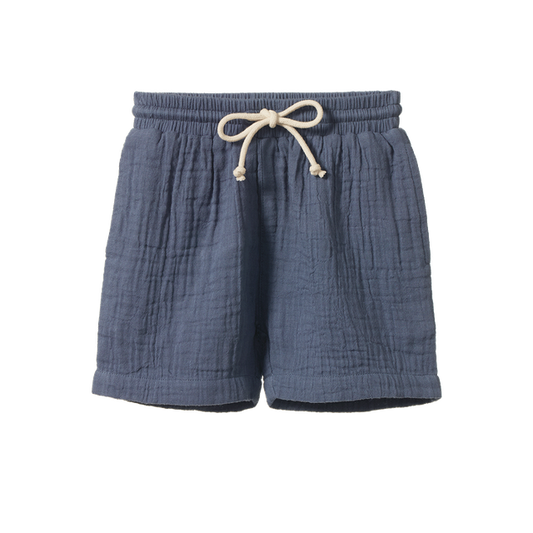Nature Baby James Shorts in Muslin Vintage Indigo, featuring lightweight muslin shorts in a soft vintage indigo blue colour. The relaxed-fit shorts have an elastic waistband with adjustable drawstring, side pockets, and a comfortable everyday design for children.